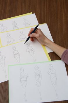 designer assessing fashion drawings on the collection of clothes