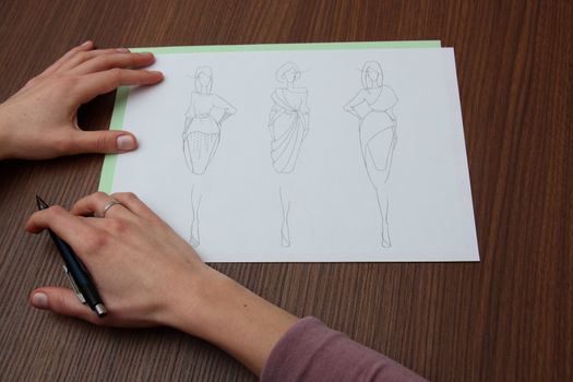 designer assessing fashion drawings on the collection of clothes