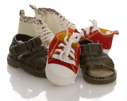 pile of baby or infant shoes with reflection on white background