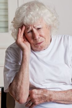 Portrait of a senior woman holding her head in pain .