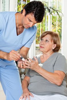 Male nurse checking sugar level of patient through glucometer