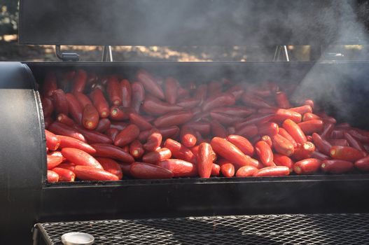 Large batch of hot chili peppers being smoked on a grill