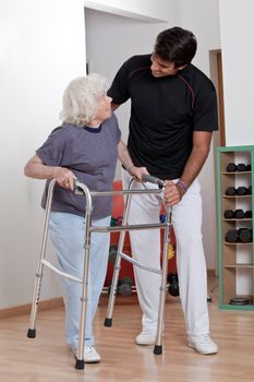 A therapist assisting a senior woman onto her walker.