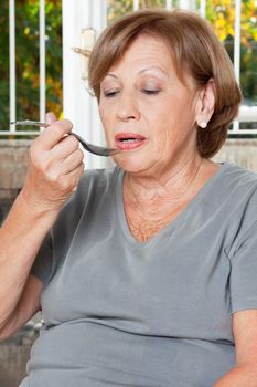 Senior woman taking medicine with spoon