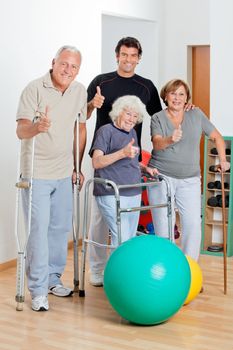 Portrait of disabled senior people with trainer showing thumbs up sign