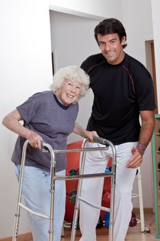 A therapist assisting a senior woman onto her walker.