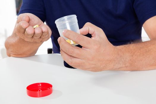 Mid section of senior man holding pills and bottle