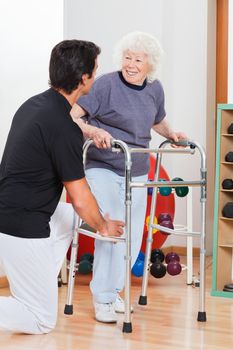 Happy senior woman with walker looking at trainer