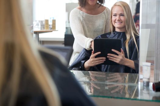 Young woman with digital tablet showing hairstyle to hair dresser