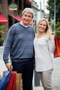 Portrait of a couple with shopping bags standing outdoors