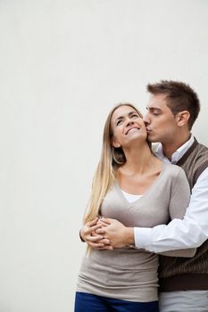 Young man kissing a beautiful woman over colored background