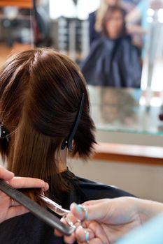 Close up of hairdresser giving a haircut to female customer at parlor