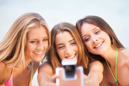 three teenager beautiful girls taking selfie with old camera on the beach