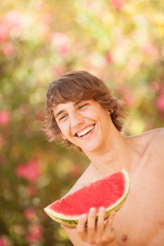 Portrait of a beautiful young man eating watermelon