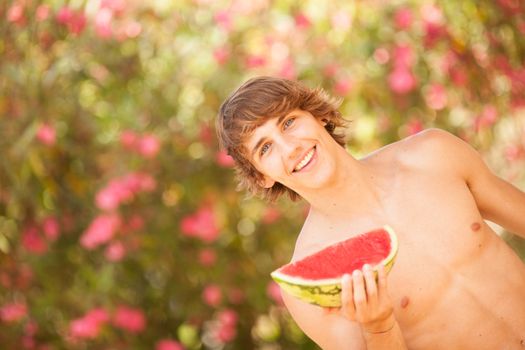 Portrait of a beautiful young man eating watermelon