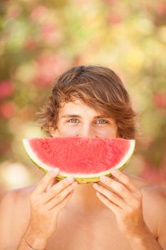 Portrait of a beautiful young man eating watermelon
