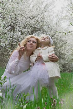 Happy mother and daughter among spring garden blossom