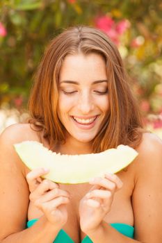 Portrait of a beautiful young woman eating melon