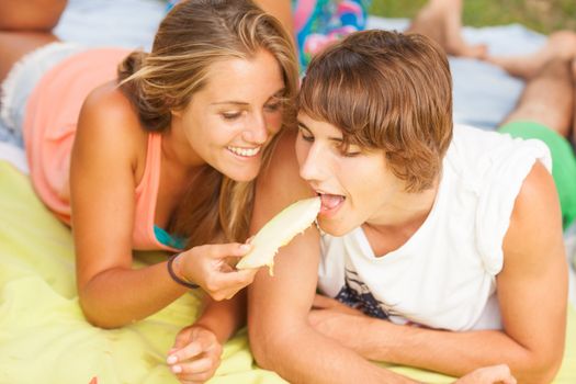 Portrait of a young beautiful couple eating melon