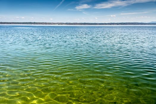 View of Lake Starnberg in Tutzing in Germany on the water, the other shore and blue sky with white clouds