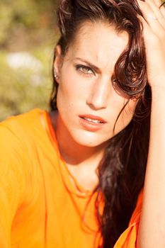 Portrait of young beautiful model posing on outdoors with orange shirt