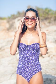 Sexy vintage model in swimsuit posing on the beach with glasses