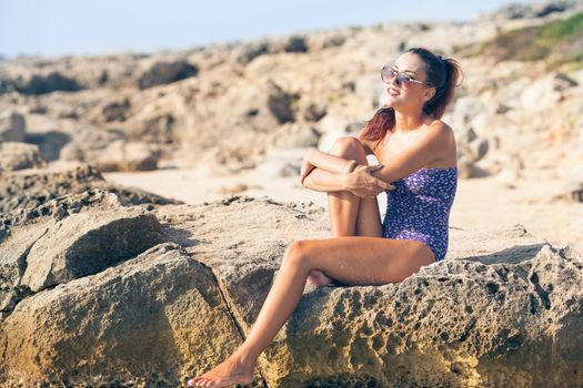 Sexy vintage model in swimsuit posing on the beach with glasses