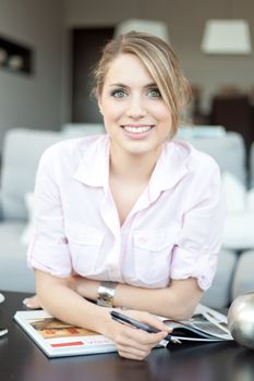 young beautiful woman smiling with printed catalog and pen