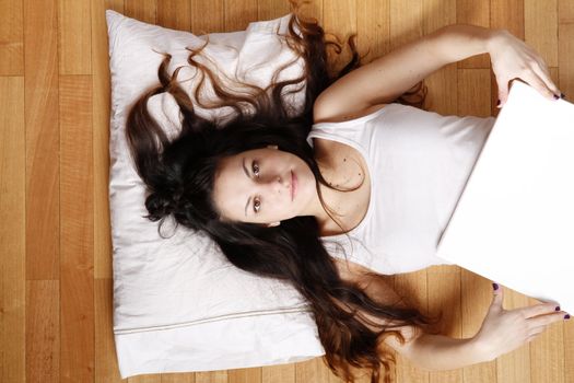 A young adult woman lying on the floor with a blank canvas.