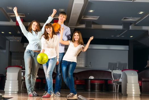 Group of young friends playing bowling, spending time with friends