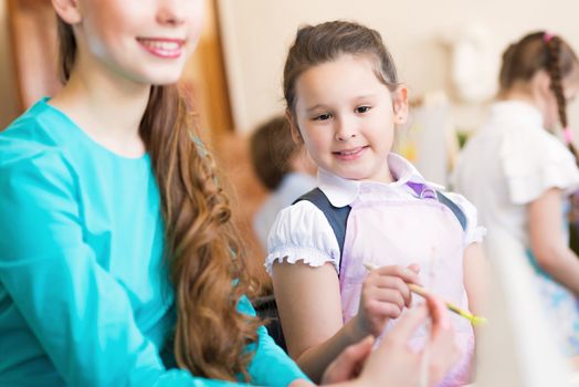 girl in the school, near the teacher and other children