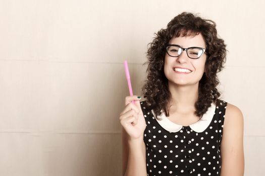 A young woman in a vintage dress holding a pen.