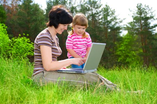 Little girl and mother with laptop outdoor