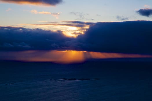 Scenic sun rays behind clouds during night in the arctic Norway