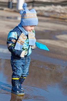 Little boy goes on a pool in rubber boots