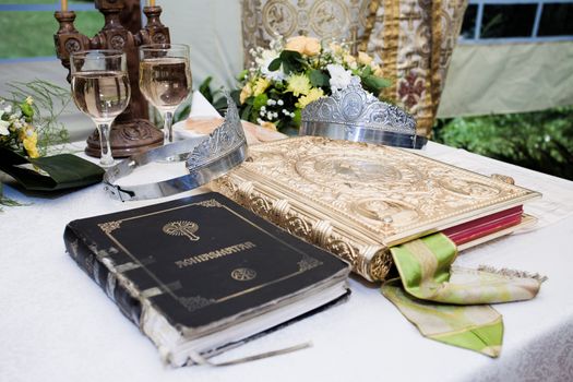 Wedding crowns, bible and wine glasses prepared for ceremony