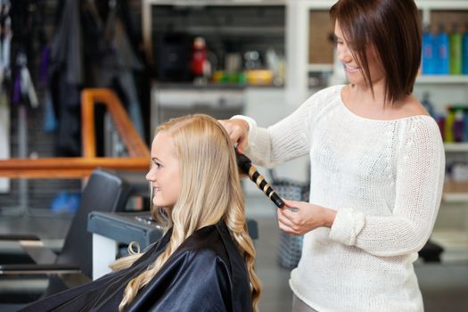 Young woman getting her curled by a stylist at hair salon