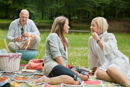 Friends visiting and preparing a barbecue for outdoor picnic