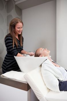 Attractive young blond woman having her hair rinsed by a stylist in a beauty salon