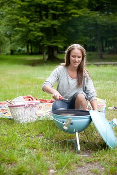 Happy young adult starting a BBQ in the park