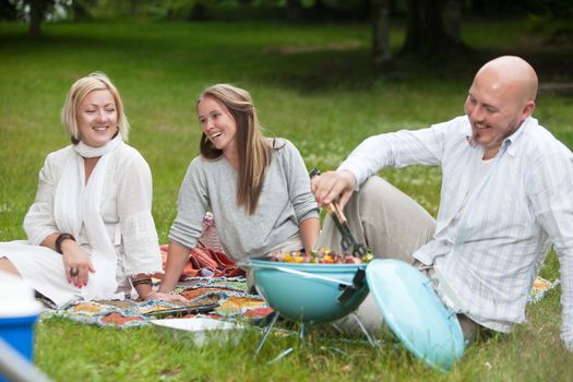 Friends laughing and having fun in park eating barbecue