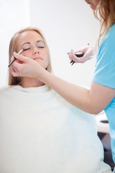 Make-up artist woman apply eyeshadow with brush .