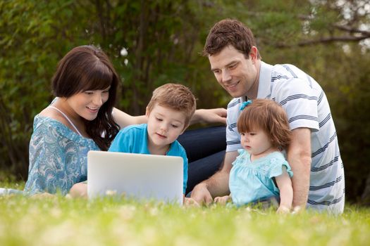Happy family together outdoors with computer