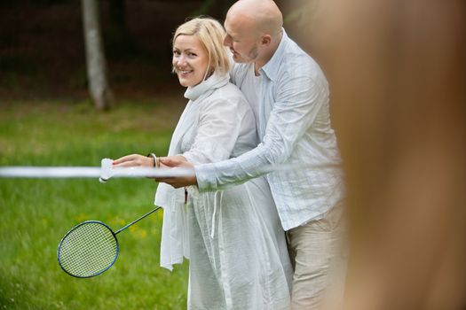 Portrait of mature couple in casual wear playing badminton together on a weekend outing