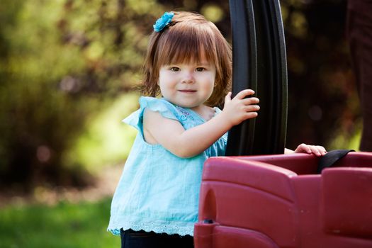 Portrait of an adorable young girl outdoor in park with wagon
