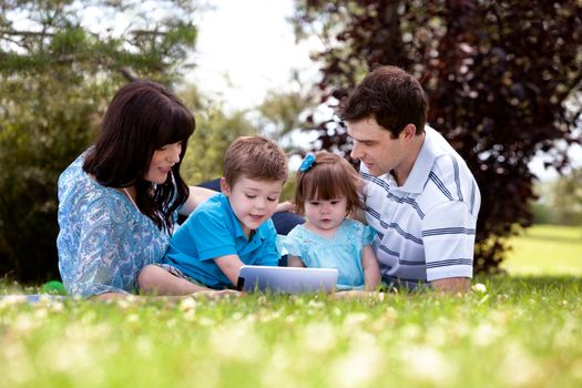 Happy family of four using a digital tablet outdoors