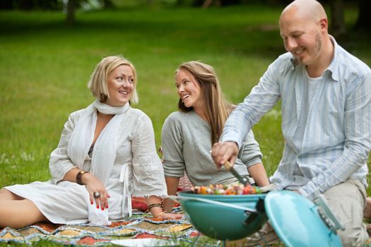 Two women talking while having a barbecue picnic in park