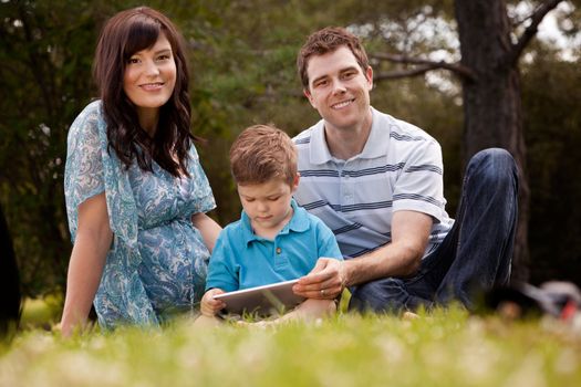 Portrait of a happy family in a park using a digital tablet
