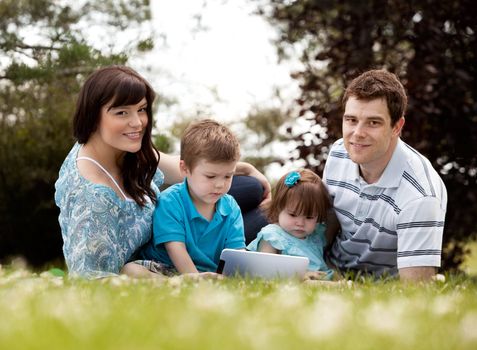 Happy young family outdoors with digital tablet