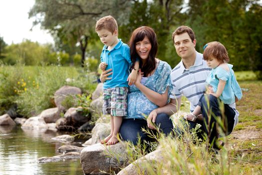 Portrait of happy good looking family near a lake in a park